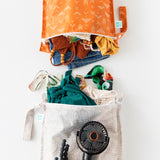 Bumkins Wet Bag 2 Pack: Wander + Grounded holds clothes, swim wear, and a black fan on a white background.