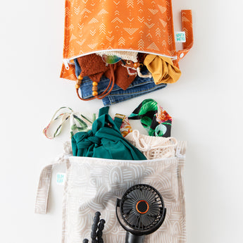 Bumkins Wet Bag 2 Pack: Wander + Grounded holds clothes, swim wear, and a black fan on a white background.