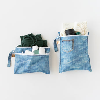 Roamio by Bumkins Wet Bag + Wet/Dry Clutch Set: Denim On Denim rests on a white background, holding clothes & toiletries.