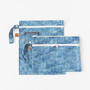 Roamio by Bumkins Wet Bag + Wet/Dry Clutch Set: Denim On Denim lays overlapped on a white background.