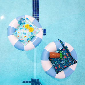 Bumkins Wet Bag 2 Pack: Ocean Life and Jungle lays in blue & white striped inner tubes with sunglasses & a palm tree shaped cup in a pool.