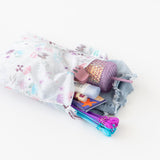 Bumkins Wet Bag: Floral lays open on a white background with a tumbler, clothes, toys, and toiletries inside.