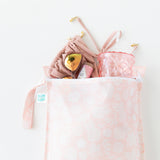 Bumkins Wet Bag: Lace lays on a white background with a swimsuit, sunglasses & tumbler peeking out.