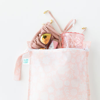 Bumkins Wet Bag: Lace lays on a white background with a swimsuit, sunglasses & tumbler peeking out.