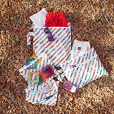 Bumkins The Chaos Coordinator Deluxe 5-Piece Set: Disney Mickey & Friends Varsity  lays on brown wood chips with toys and clothes inside.