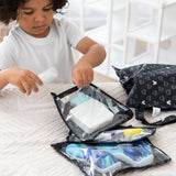 A young boy packs travel essentials in Bumkins The Chaos Coordinator Essential 4-Piece Set: Mickey Mouse Icon Black + White on a bed.