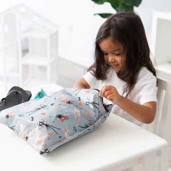 Young child opens a Bumkins Wet Bag 2 Pack: Disney Everyday Is Halloween, made from waterproof fabric, indoors.
