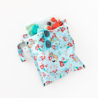 Bumkins Wet Bag: Disney Princess Ariel holds sunscreen, goggles, sunglasses, and sand toys on a white background.