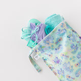 A towel, swimwear, and goggles peek out of Bumkins Wet Bag: Aloha Stitch on a white background.