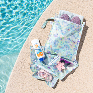 Bumkins The Chaos Coordinator Essential 4-Piece Set: Disney Aloha Stitch holds swim gear on a tan deck next to a bright blue pool.