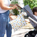 Woman with stroller uses Bumkins Wet Bag + Clear Travel Bag 3 Pack: Disney Winnie + Friends for easy travel organization.