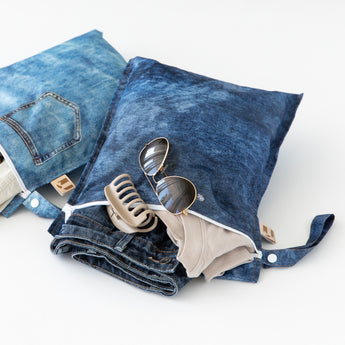 Roamio by Bumkins Wet Bag 2 Pack in Denim On Denim holds sunglasses and a beige hair clip, made from waterproof fabric.