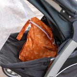 A Bumkins Wet Bag 2 Pack: Wander + Grounded sits partly hidden in a stroller basket, keeping essentials secure and stylish.
