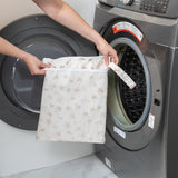 A person holds a bag from Bumkins Wet Bag + Wet/Dry Bag Set: Palm Daze in front of an open front-loading washing machine.