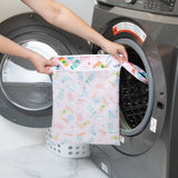 A person holds a Bumkins Wet/Dry Bag: Boots in front of a front-loading washing machine.