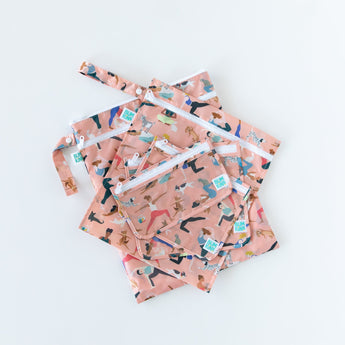 Bumkins Wet/Dry Bag: Yoga Pals lays flat on a white background underneath similar bags with matching patterns.
