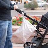 Someone pushes a stroller with Bumkins Wet/Dry Bag: Wander attached, surrounded by urban scenery and a flowerbed.