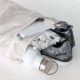 Bumkins Wet/Dry Bag: Wander fits a water bottle, book, gloves, and golf tees; gray sneakers peek out on a white background.