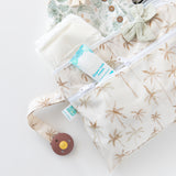 Close-up of a bag from Bumkins The Chaos Coordinator Deluxe 5-Piece Set: Palm Daze with baby clothes and essentials on a white background.