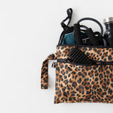 A bag from Roamio by Bumkins Wet Bag + Wet/Dry Clutch Set: Leopard holds gym gear on a white background.