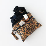 A bag from Roamio by Bumkins Wet Bag + Wet/Dry Clutch Set: Leopard holds clothes and toiletries on a white background.