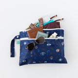 A bag from Bumkins Wet Bag + Wet/Dry Clutch Set: Evil Eye holds sunglasses, a passport, and swimwear on a white background.
