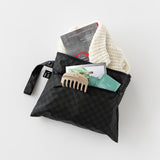 Roamio by Bumkins Wet/Dry Clutch: Rich Black holds a book, hair clip, sweater, and tea bags on a white background.