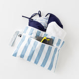 Roamio by Bumkins Wet/Dry Clutch: Nautical Stripe holds a bikini, towel, sunglasses & passport on a white background.