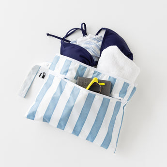 Roamio by Bumkins Wet/Dry Clutch: Nautical Stripe holds a bikini, towel, sunglasses & passport on a white background.