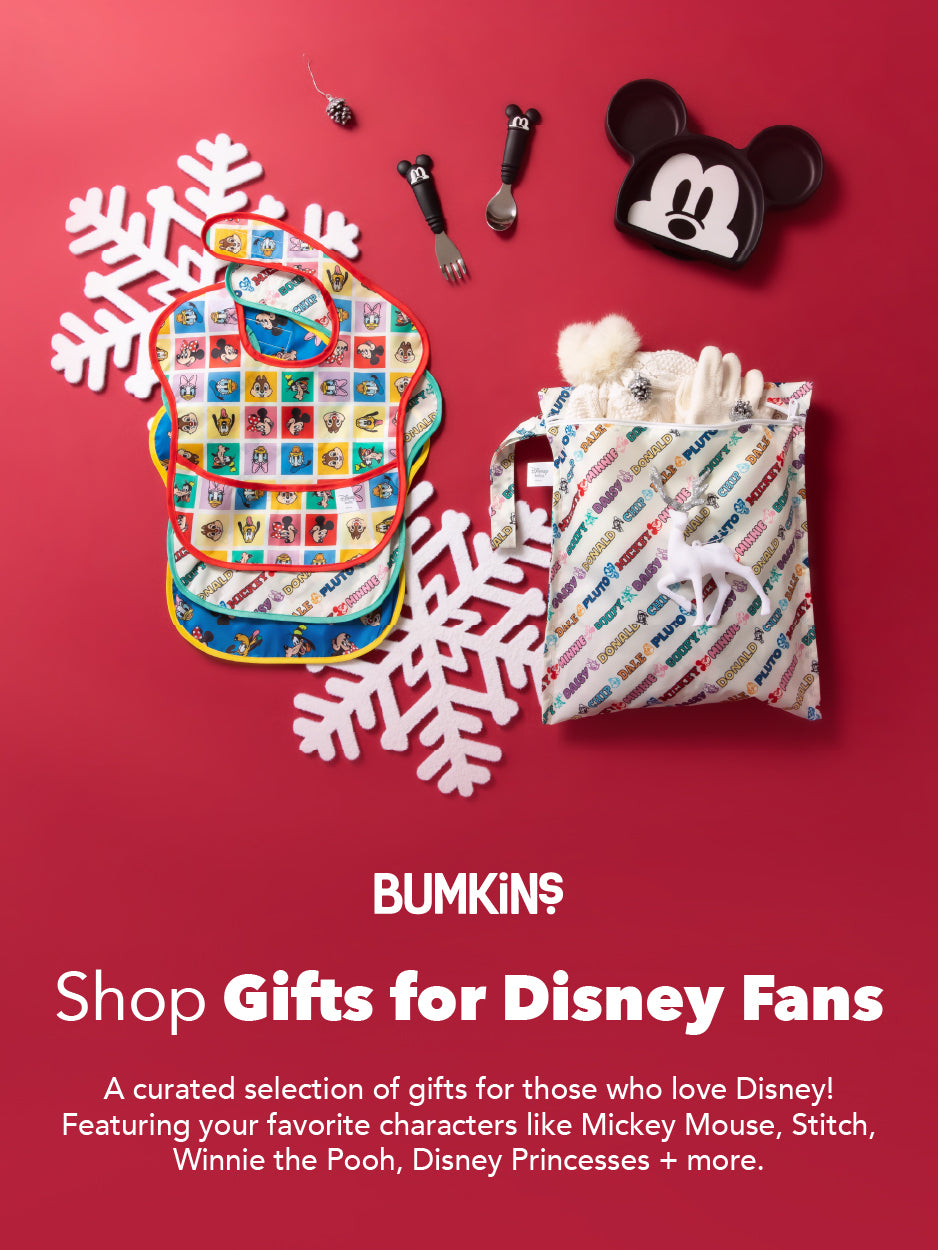 Disney-themed baby bibs, a Mickey Mouse hat, and a gift bag with gloves on a red background with white snowflakes.
