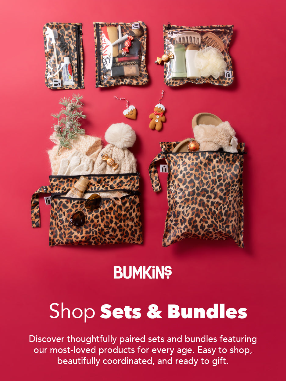 Three leopard-print Bumkins bags, one with toiletries, one with holiday gifts, and one with slippers, on a red background.