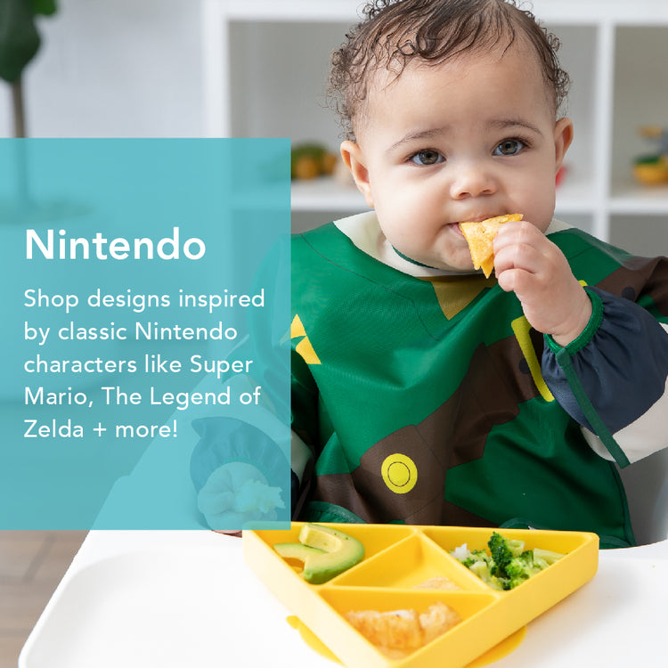 A baby in a colorful bib sits in a high chair, holding a piece of food. A divided plate with avocado and other items is in front. Text on the image promotes Nintendo-themed designs inspired by games like Super Mario and The Legend of Zelda.