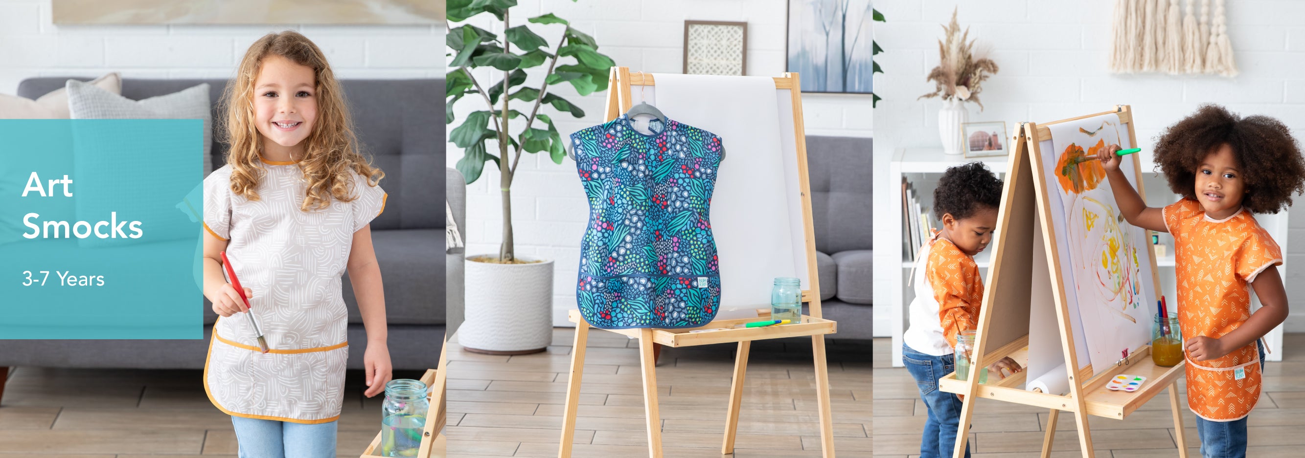 Three images showing children in art smocks. First, a girl smiles with a paintbrush. Second, a close-up of a smock on an easel. Third, two children paint on a shared canvas. Text reads: Art Smocks 3-7 Years.