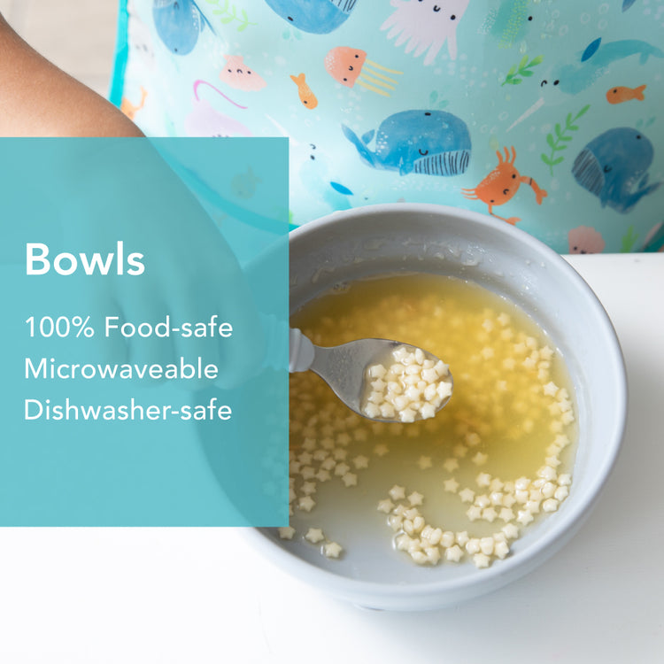 A bowl filled with small, star-shaped pasta and broth sits on a white surface. A hand is holding a spoon over the bowl. Text on the image reads: Bowls - 100% Food-safe, Microwaveable, Dishwasher-safe. The person is wearing an ocean-themed apron.