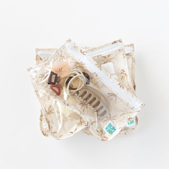 Bumkins Clear Travel Bag 3 Pack: Palm Daze sits stacked on a white background, neatly holding small items like clips and hair ties.