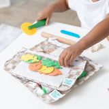 A child plays with a toy pizza cutter and play dough as Bumkins Clear Travel Bag 3 Pack: Sand Check with art supplies sits nearby on a table.