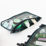 Close-up of Bumkins Clear Travel Bag 3 Pack: Starry Cactus filled with green & white skincare items on white background.