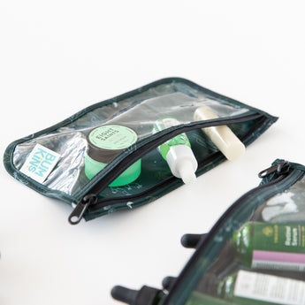 Close-up of Bumkins Clear Travel Bag 3 Pack: Starry Cactus filled with green & white skincare items on white background.