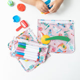 A child's hands use Play-Doh next to 3 bags from Bumkins The Chaos Coordinator Essential 4-Piece Set: Boots with art supplies on a table.