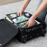 A person packs Bumkins Clear Travel Bag 3 Pack: Rich Black filled with toiletries into an open black suitcase on a gray rug.
