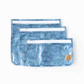 Roamio by Bumkins Clear Travel Bag 3 Pack: Crushed Denim lays overlapped on a white background.