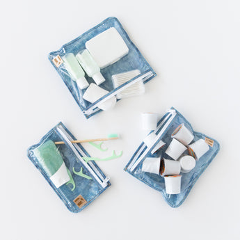 Roamio by Bumkins Clear Travel Bag 3 Pack: Crushed Denim holds toiletries and coffee pods on a white background.