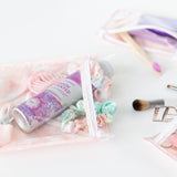 Close-up of Bumkins Clear Travel Bag 3-Pack: Lace on a white background with hair accessories and makeup inside.