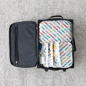 Open suitcase on gray carpet packed with Bumkins Disney Mickey & Friends Varsity packing cubes and clear travel bags.