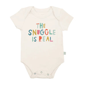 Finn and Emmas Organic Bodysuit, Snuggle Is Real, is cream-colored with colorful text: THE SNUGGLE IS REAL on the front.