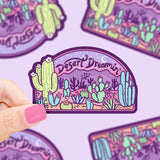 A hand holds a Turtle Soups Desert Dreaming durable waterproof vinyl sticker, featuring cacti and a desert scene under a starry sky.