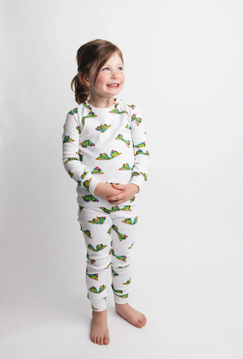 A smiling child in Lovedbabys Organic Long Sleeve PJs, Butterfly, stands against a white background wearing eco-friendly dyes.