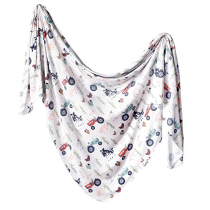 The Copper Pearl Knit Swaddle Blanket, Jo, features colorful farm animals and tractors on a white background—perfect for cozy naps.