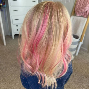 Blonde hair with Piggy Paint Pink highlights on someone in a navy polka dot shirt. Drawers and a basket in the background.