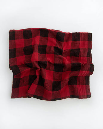 A Cotton Swaddle in red plaid by Little Unicorn is crumpled on a white surface.